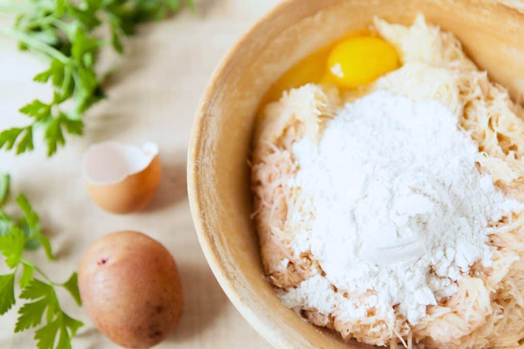After grating the potatoes, squeezing out the water, mixing the mixture with egg, onion, flour, and salt. (Source: daringgourmet.com)